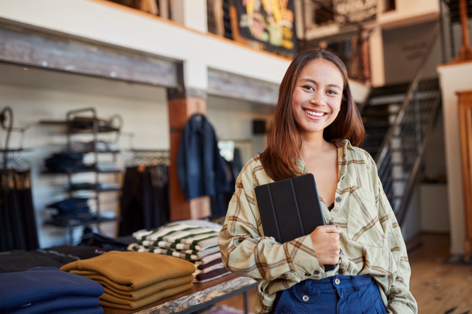 Smiling clothing store associate holding a tablet on the shop floor